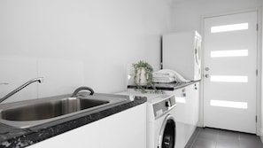 A modern kitchen with a stainless steel sink, a built-in oven, and a washing machine.