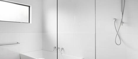 Un baño moderno con bañera, ducha y un taburete de madera.