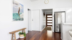 Eine moderne Küche mit weißen Schränken, einem Edelstahlkühlschrank und einer Holzbank mit Pflanze.