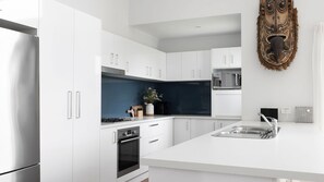 Eine moderne Küche mit weißen Schränken, einer blauen Spritzschutzwand und einer zentralen Kochinsel mit Spüle.