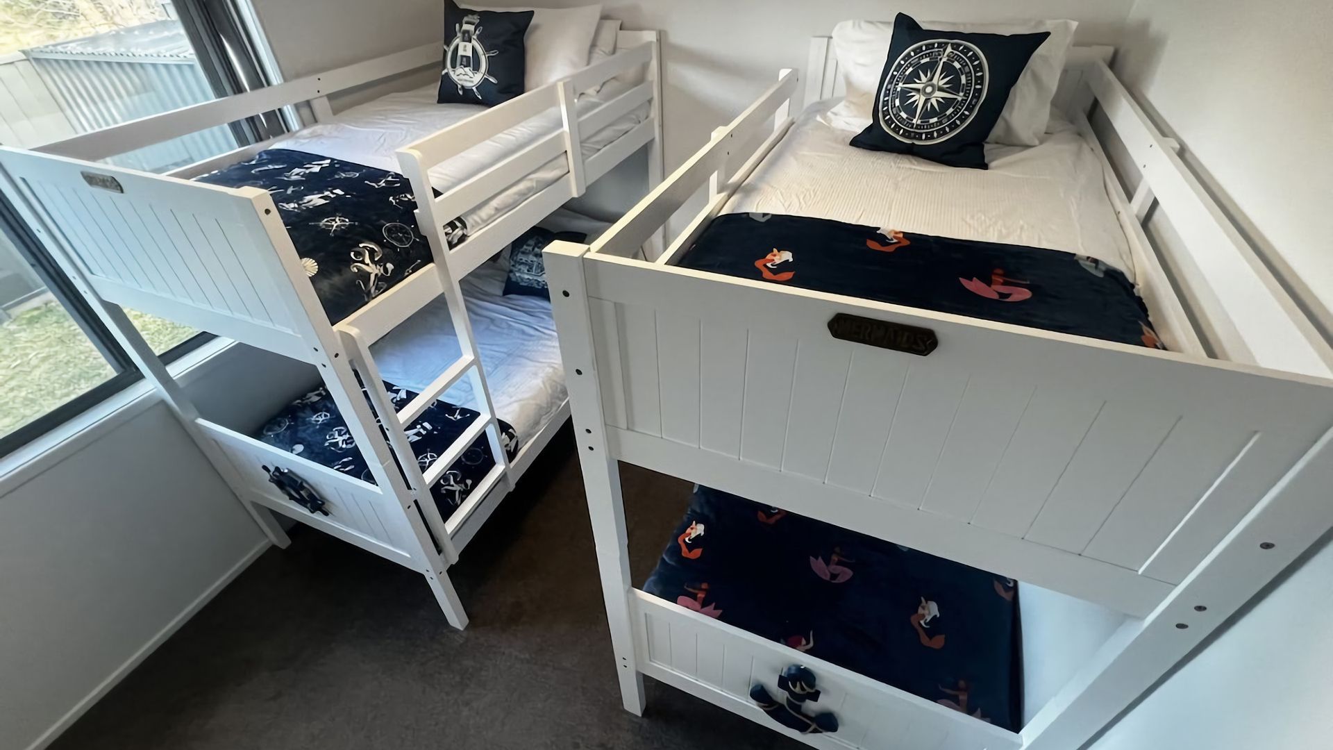 A room with three bunk beds, each with a different design.