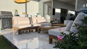 Un espace de vie extérieur moderne comprenant un canapé, une table basse et un barbecue.