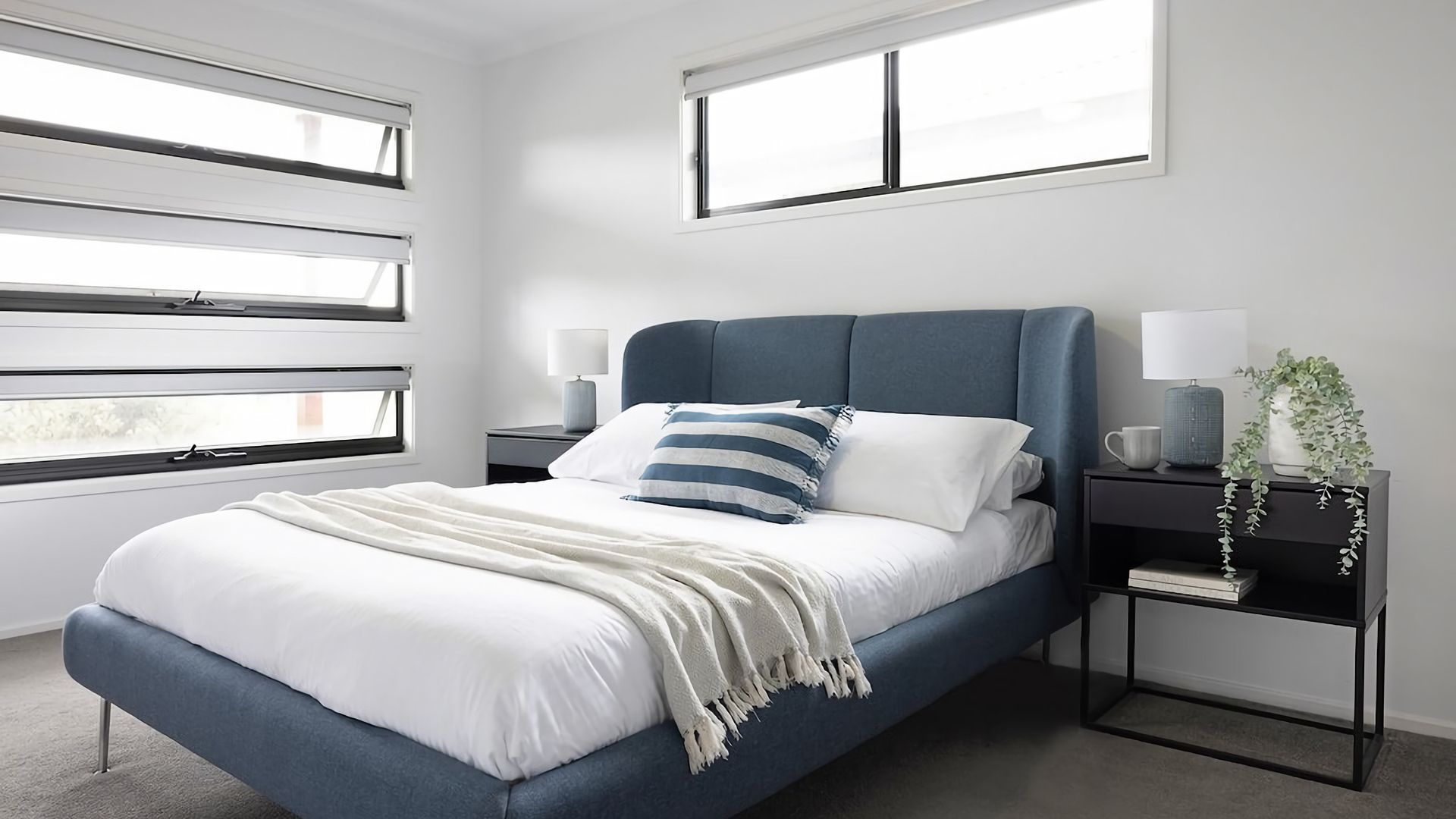 A modern bedroom with a bed, nightstands, and a window.