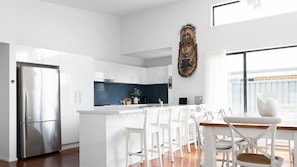 A modern kitchen with white cabinets, a stainless steel refrigerator, and a blue accent wall.
