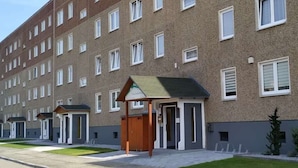 A multi-story hotel with a brick facade, a small entrance with a green awning, and a well-maintained lawn. - Spreewald-Familienherberge (Lübbenau/Spreewald)