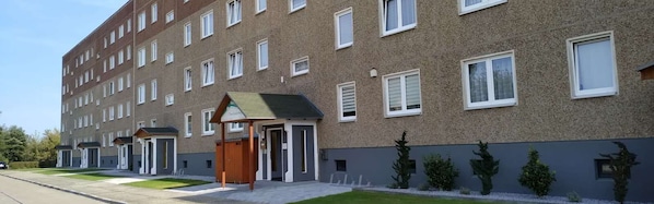 Un hotel de varios pisos con fachada de ladrillo, una pequeña entrada con toldo verde y un césped bien cuidado.