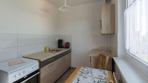 A compact kitchen with a stove, sink, and wooden cabinets. - Spreewald-Familienherberge (Lübbenau/Spreewald)