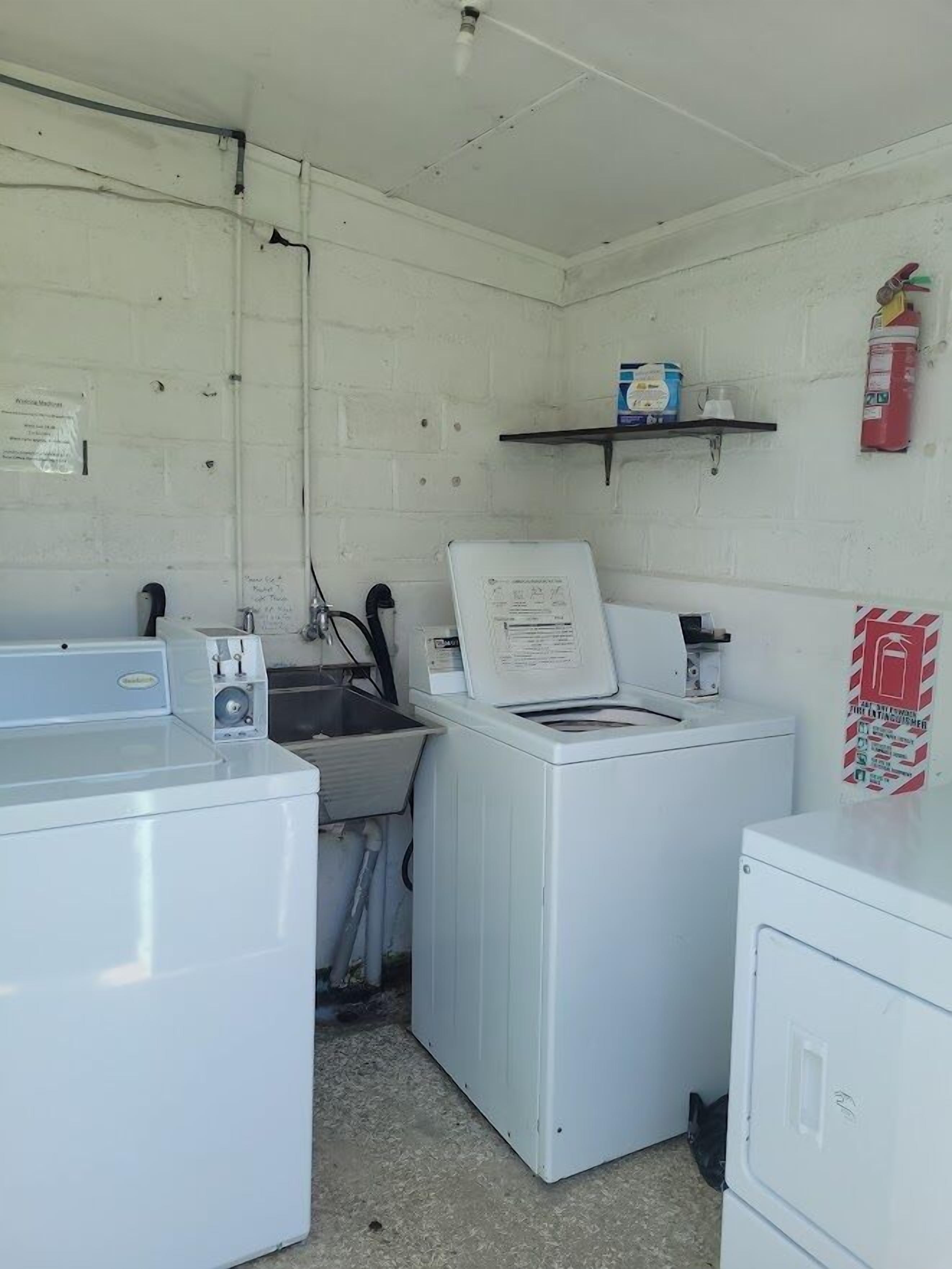A laundry room with a washing machine, dryer, and a shelf with cleaning supplies.