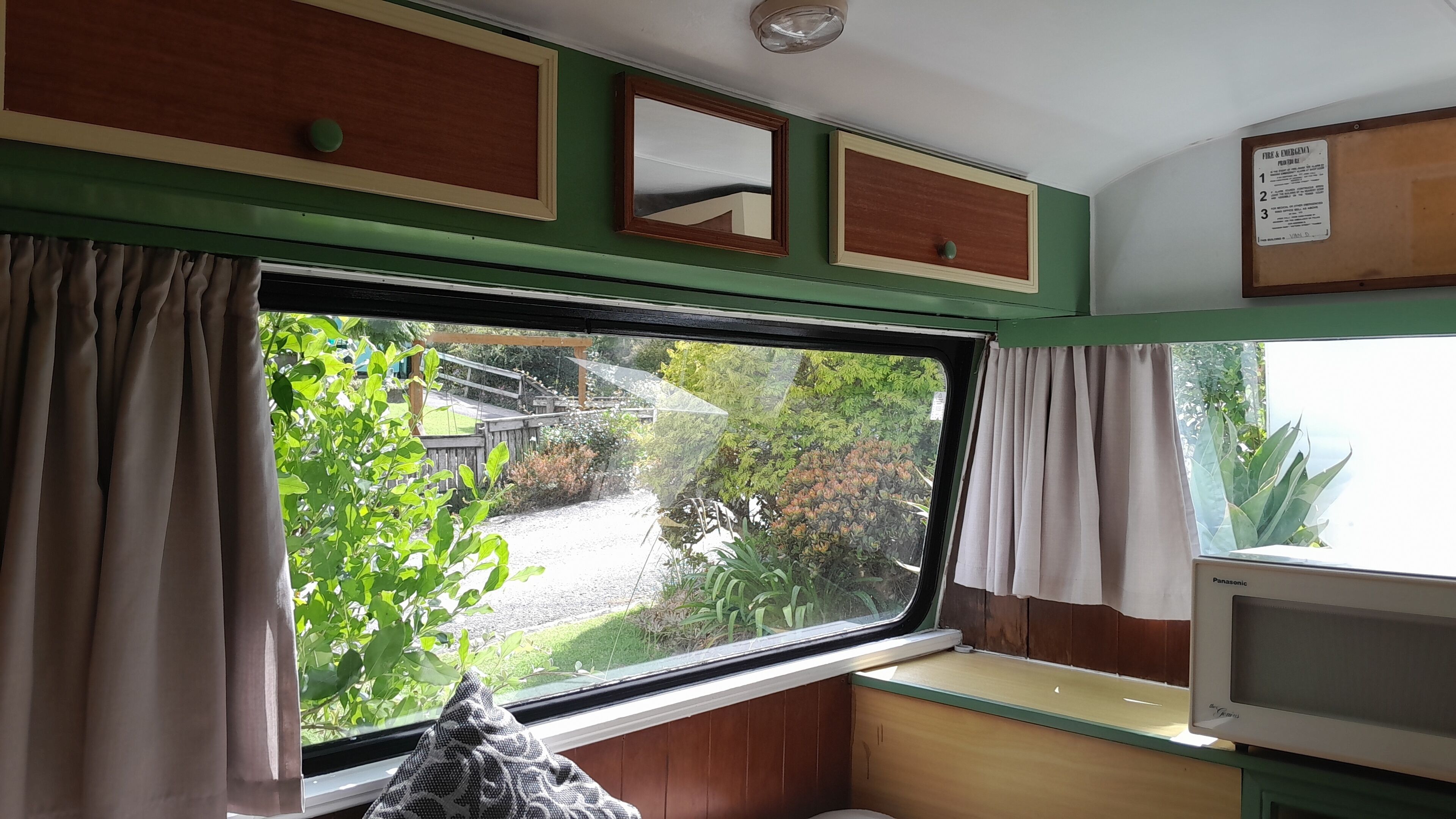Ein Zimmer mit großem Fenster, Holzvertäfelung, einer Bank und einem kleinen Tisch.