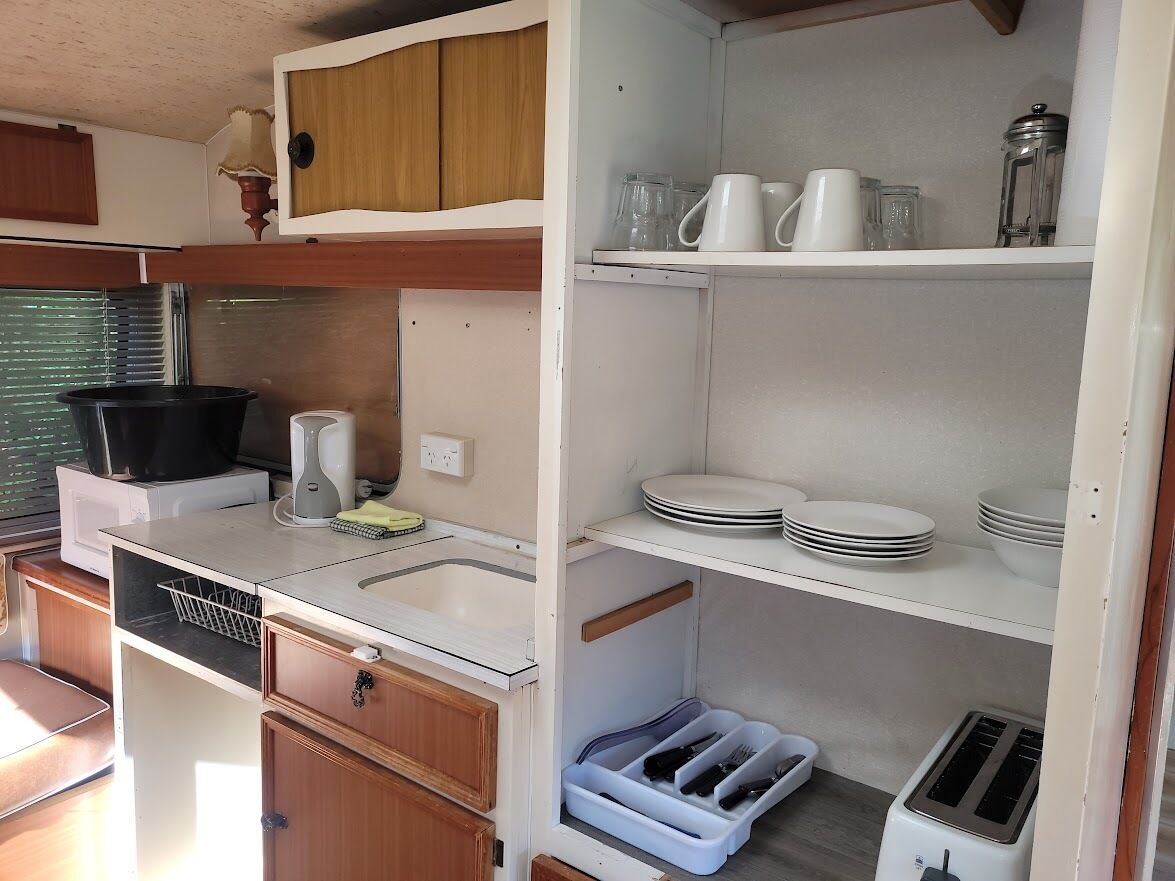 A compact kitchenette with a sink, stove, and storage shelves.