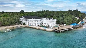 Un gran edificio blanco con varios balcones, una piscina y un muelle que se adentra en el agua.