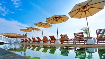 Una piscina al aire libre, sombrillas, sillones reclinables de piscina
