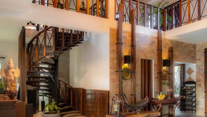 A spacious lobby with a spiral staircase, a wooden bench, and a wine rack. - Bunwin Siem Reap (Siem Reap)