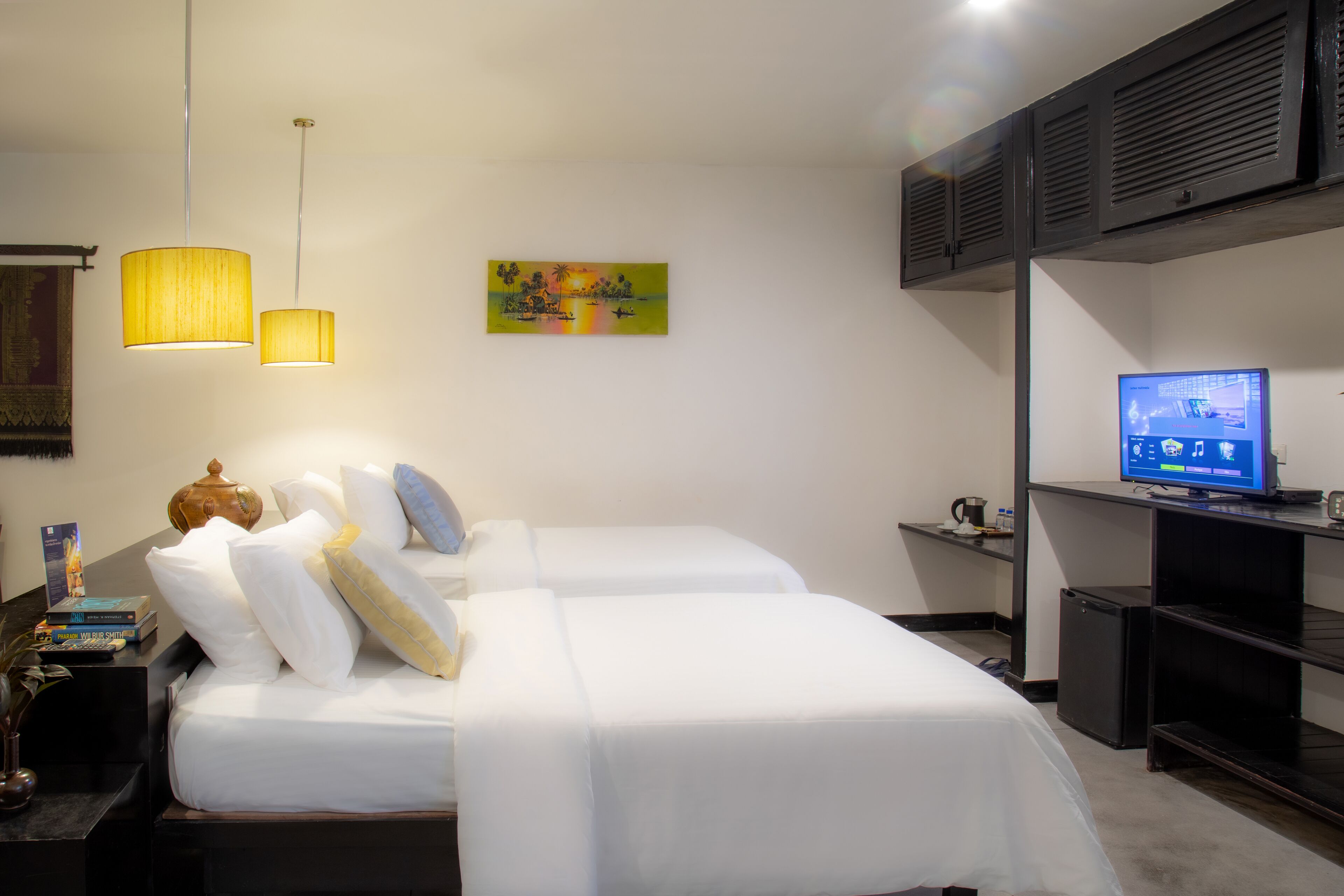 A hotel room with two beds, a television, and a painting on the wall.