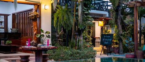 An indoor pool area with a wooden deck, a stone bench, and a signboard advertising spa treatments.