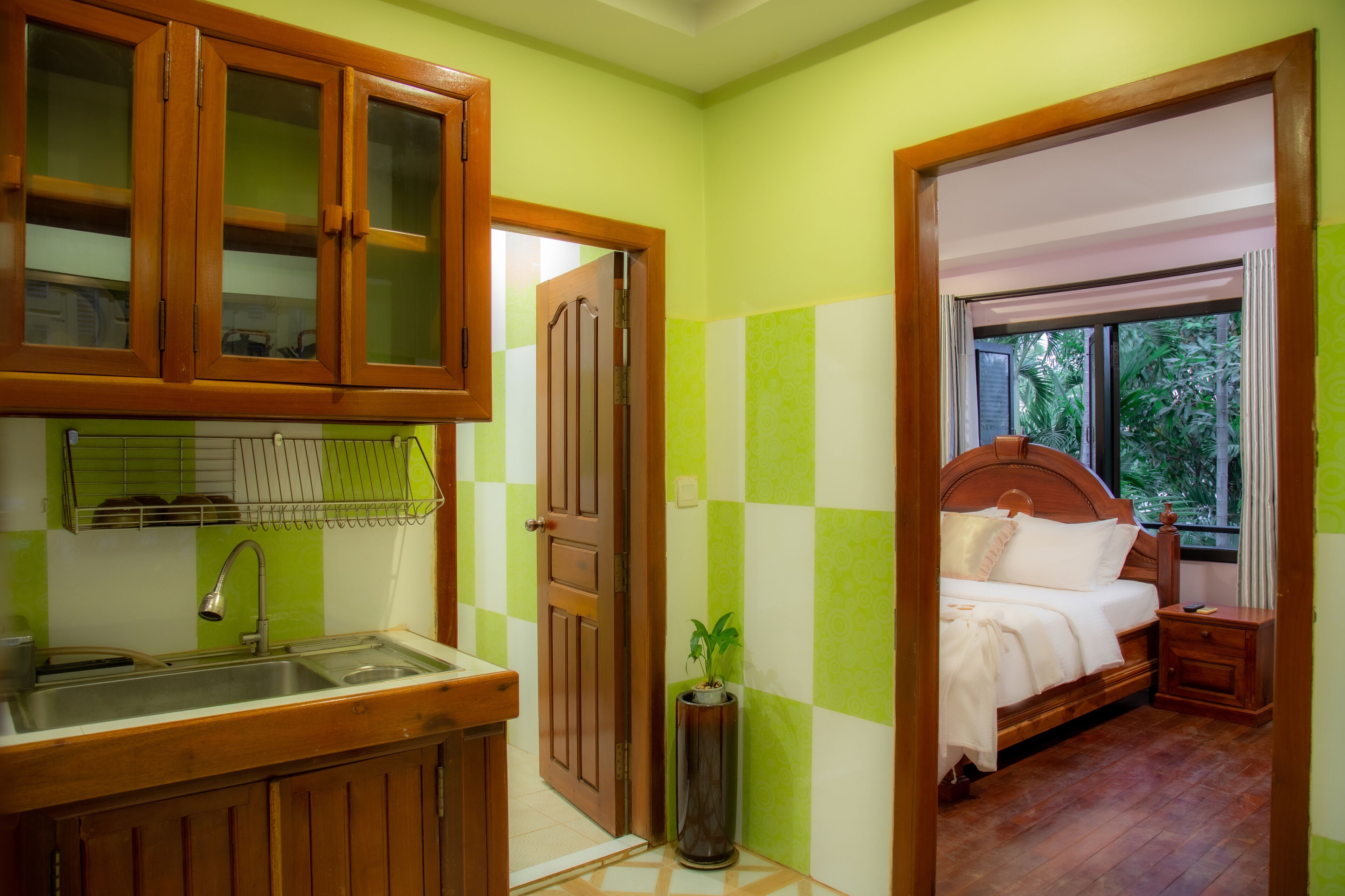 A room with a wooden cabinet, a sink, a bedside table, and a bed.