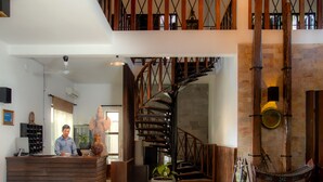 A reception area with a wooden reception desk, a spiral staircase, and a seating area with a hammock. - Bunwin Siem Reap (Siem Reap)