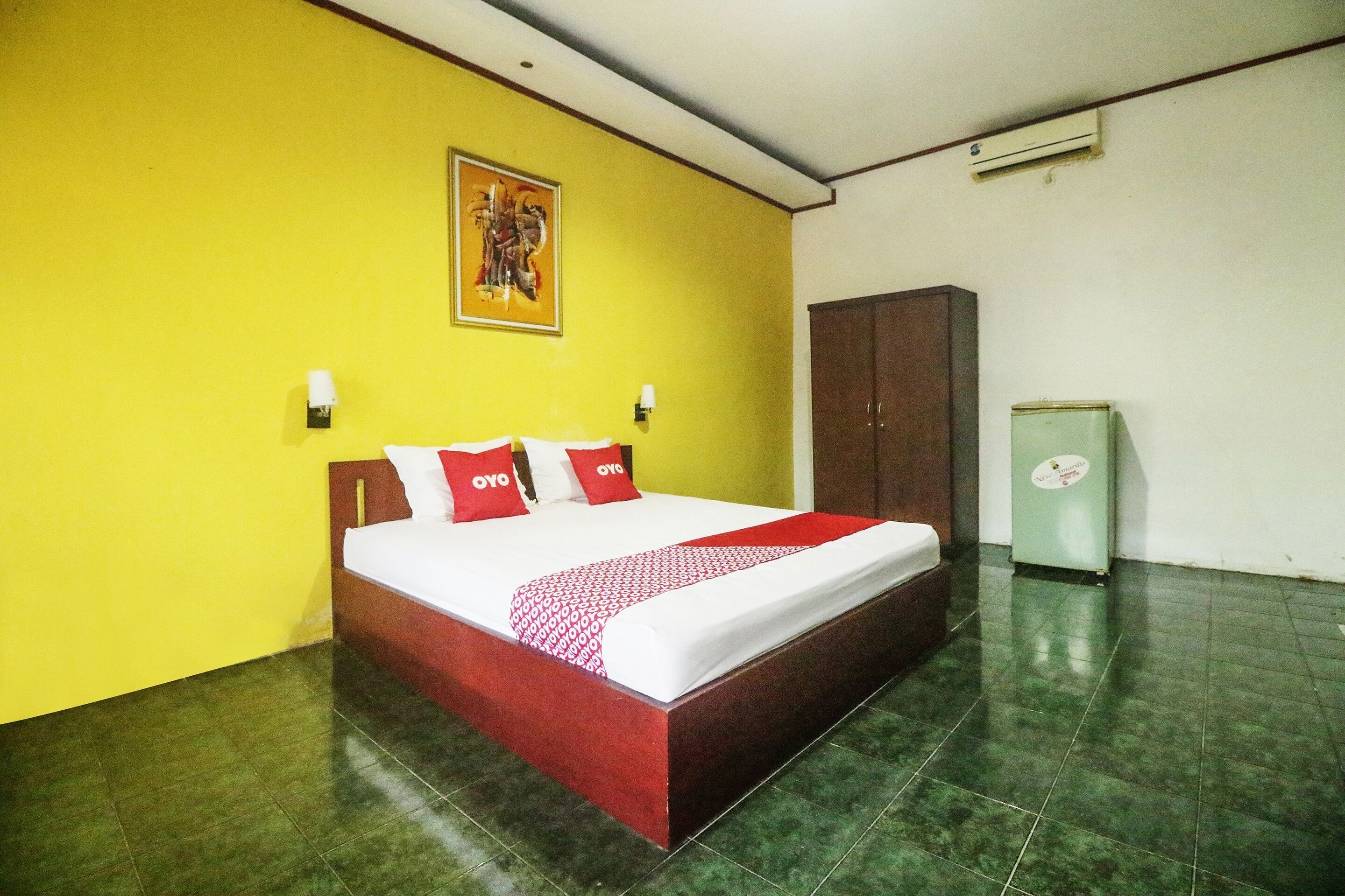 A hotel room with a bed, a wardrobe, and a small refrigerator.