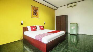 A hotel room with a bed, a wardrobe, and a small refrigerator.