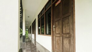 A corridor with a tiled floor, a wooden door, and a sign above the door. - Hotel O Nyi Rindang Near Puskesmas Jekan Raya (Palangkaraya)