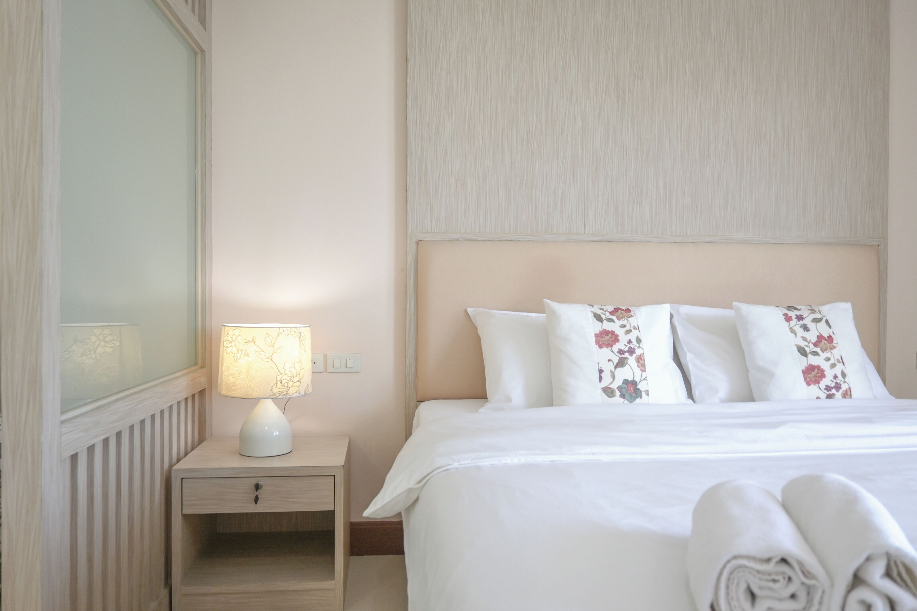 A hotel room with a bed, a nightstand with a lamp, and a mirror.
