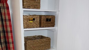 A white storage unit with wicker baskets on shelves. - Tiny House Train-Eco Stay (Upper Hutt)