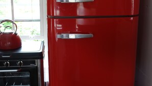 A red vintage Smeg refrigerator with two doors, a black stove, and a kettle on top. - Tiny House Train-Eco Stay (Upper Hutt)