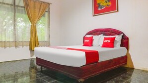 Een hotelkamer met een bed, gordijnen, een schilderij en een betegelde vloer.