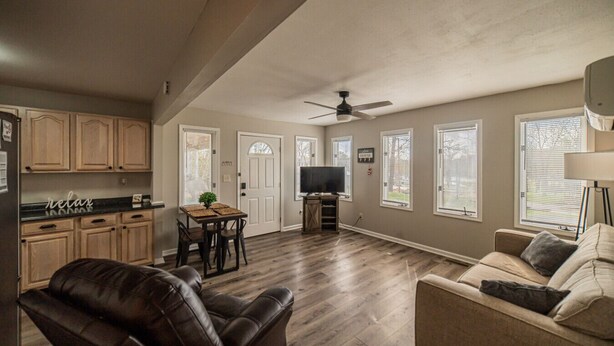 A spacious living area with a sofa, a leather chair, a dining table with chairs, a television, and a ceiling fan. - Charming KY Lake Condo Short Walk to Lake (Gilbertsville)