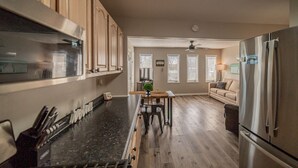 A kitchen with wooden cabinets, a black countertop, a dining table with chairs, a refrigerator, and a ceiling fan. - Charming KY Lake Condo Short Walk to Lake (Gilbertsville)