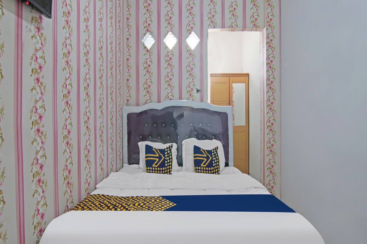 Une chambre à coucher avec un lit, un papier peint à motifs floraux, une armoire en bois et un téléviseur.