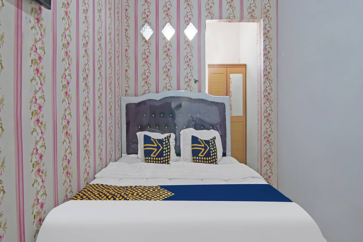 Ein Schlafzimmer mit Bett, floralem Wandpapier, einem Holzschrank und einem Fernseher.