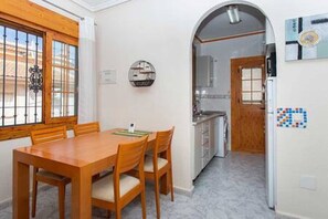 A dining area with a wooden table and chairs, a kitchen with a built-in oven, and a refrigerator with a blue and white design. - CH Villa Africa La Marquesa Golf (Ciudad Quesada) (Ciudad Quesada)
