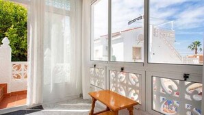 A room with a wooden bench, large windows with a view of buildings, and a patterned window blind. - CH Villa Africa La Marquesa Golf (Ciudad Quesada) (Ciudad Quesada)