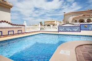 Una piscina con cerca blanca y cubierta de baldosas.