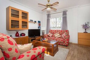 A living room with a sofa, a television, a wooden cabinet, and a ceiling fan. - CH Isamar Park Doña Pepa (Ciudad Quesada) (Ciudad Quesada)