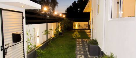 Una casa moderna con un porche cubierto, un pequeño jardín y un sendero que lleva a la entrada.