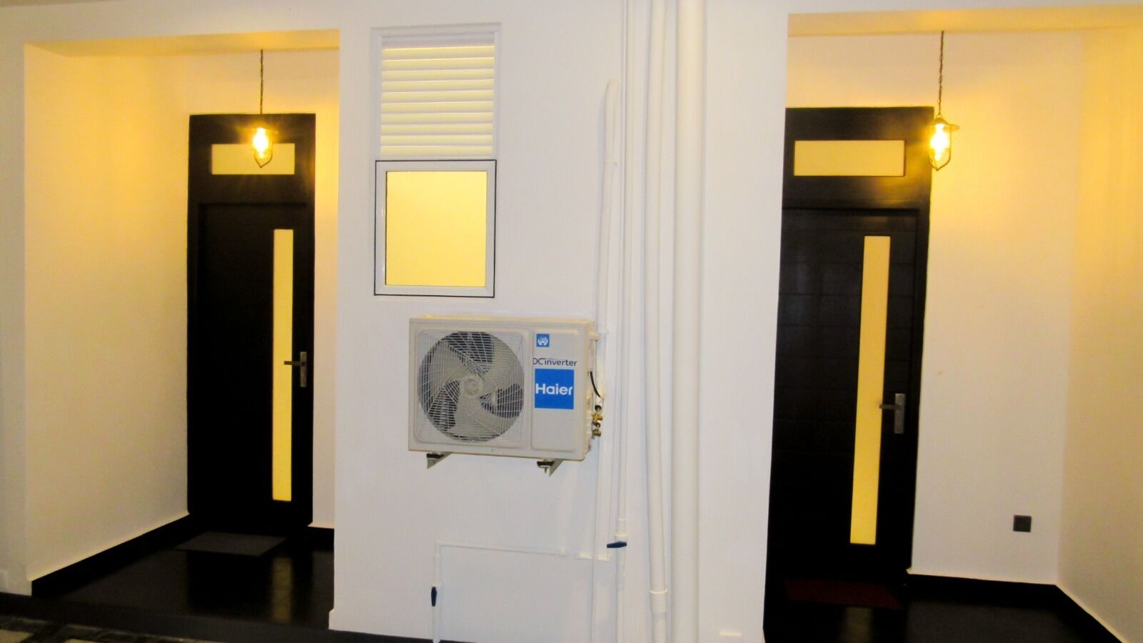 A hallway with two doors, a wall-mounted fan, and a light fixture.