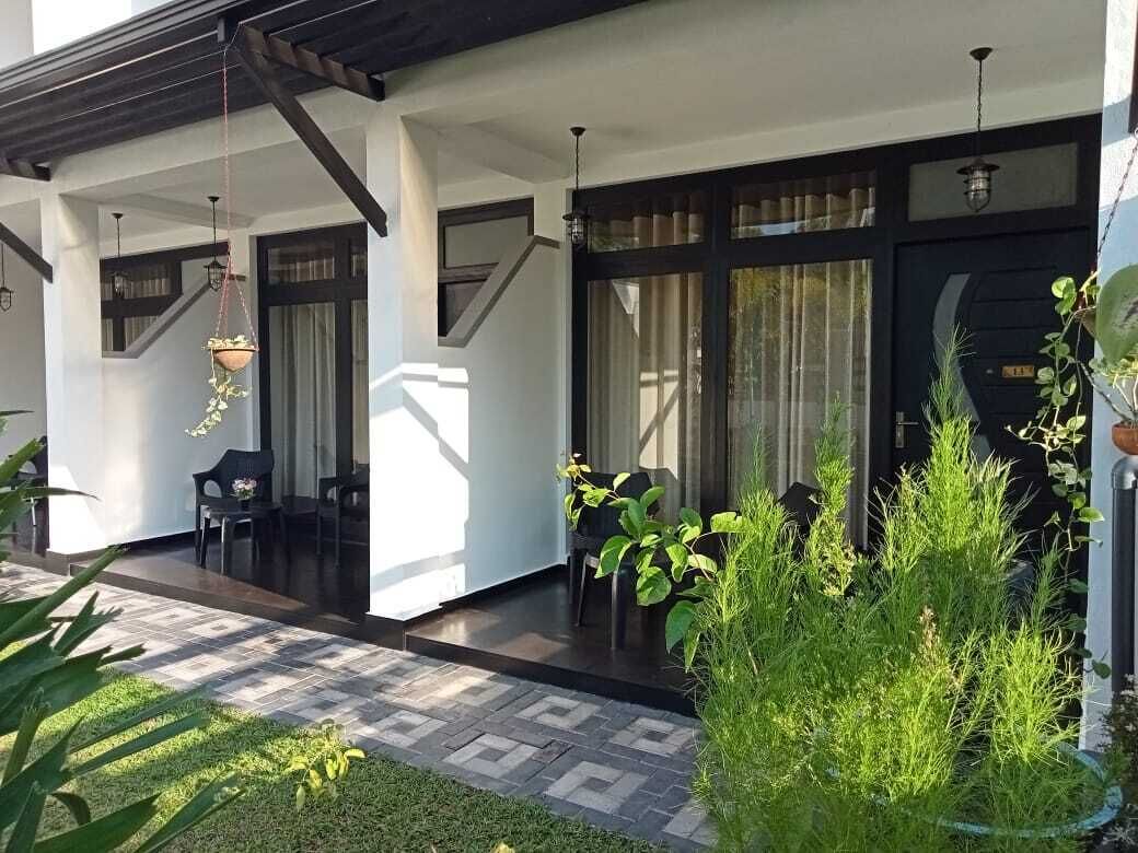Una casa moderna con un porche cubierto, mobiliario exterior y plantas en macetas.