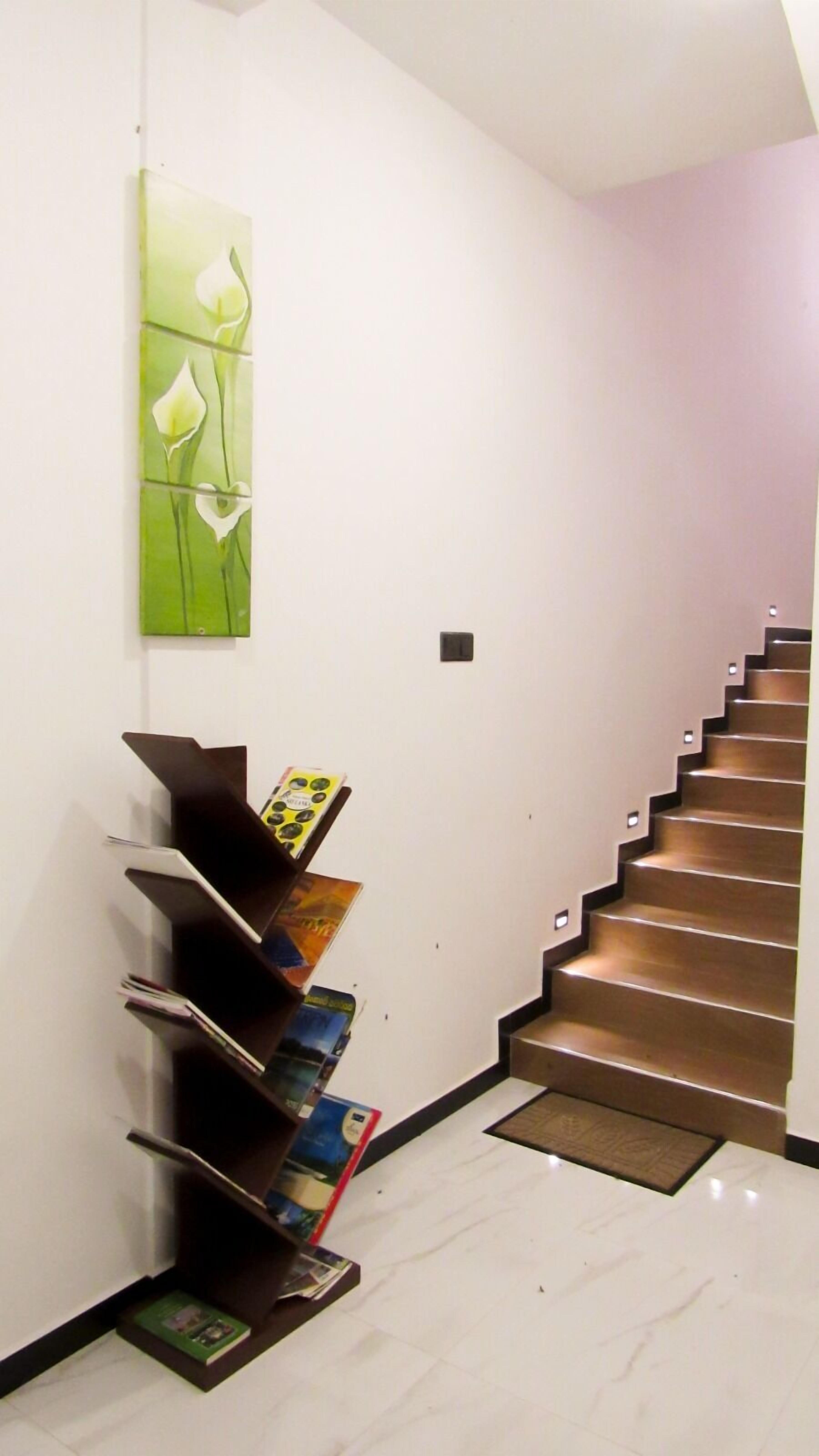 Un escalier moderne, avec un sol en marbre, mène à un palier.