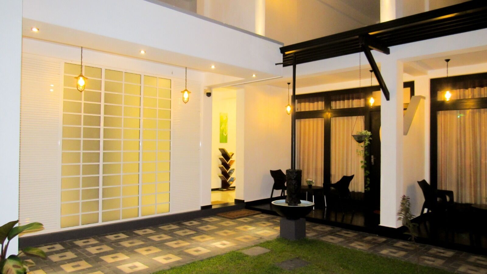 A well-lit outdoor patio area with a patterned floor, a seating arrangement, and a decorative fountain.