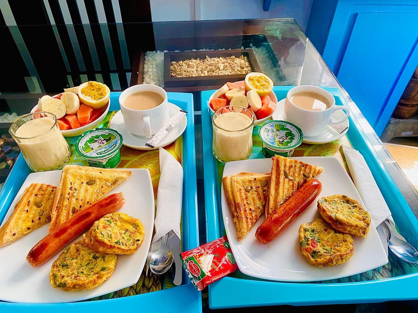 Un plateau de petit-déjeuner contenant divers aliments, notamment des toasts, des saucisses et un assortiment de fruits et de légumes.