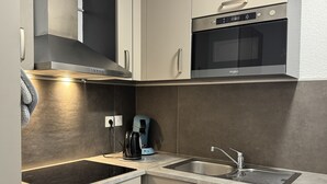 A modern kitchen with a built-in oven, microwave, and a coffee maker.