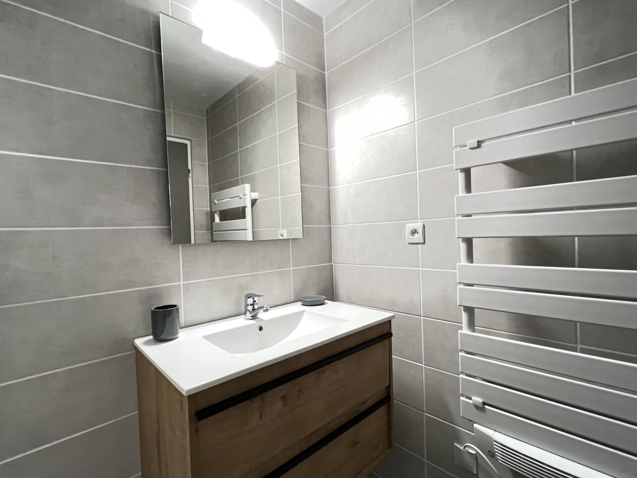 Ein modernes Badezimmer mit Waschbecken, Holzschrank und Handtuchhalter.