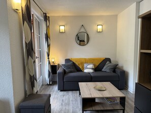 Ein kompakter Wohnbereich mit Sofa, Couchtisch und Beistelltisch mit Lampe.