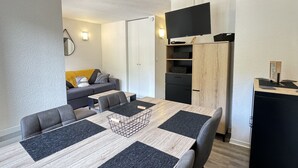 A compact living space with a dining table, sofa, and built-in TV.
