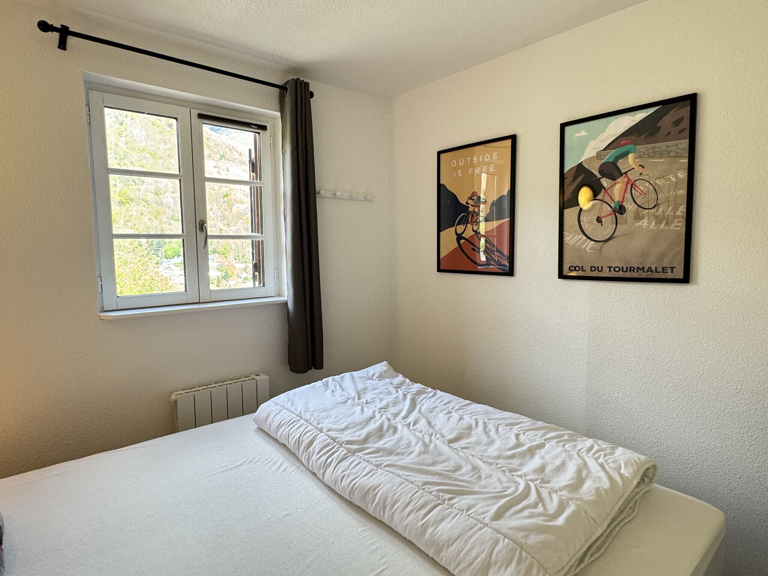 Ein Schlafzimmer mit einem Bett, einem Fenster mit Vorhängen und zwei an der Wand befestigten Postern.