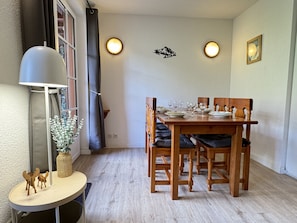 A dining area with a wooden table set for four, a lamp, and a vase with a plant.