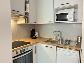 A compact kitchen with a built-in oven, a microwave, a coffee maker, and a dishwasher. - Duplex + terrasse panoramique.Parking.Piscine été (Cauterets)