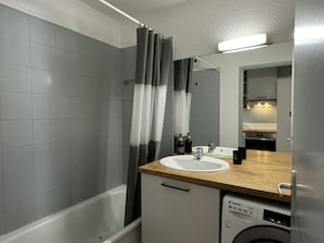 A modern bathroom with a bathtub, a sink, and a washing machine.